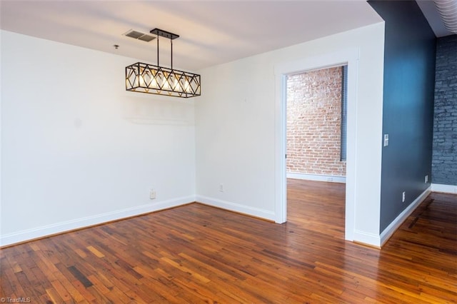 unfurnished dining area featuring brick wall and dark hardwood / wood-style flooring