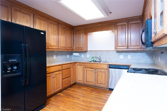 kitchen featuring black appliances, tasteful backsplash, light hardwood / wood-style flooring, and sink