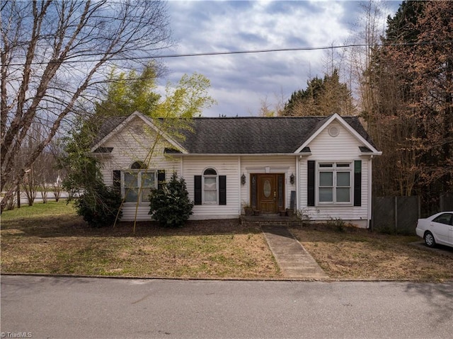 ranch-style home featuring a front yard, fence, and roof with shingles