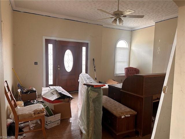 foyer entrance with ceiling fan, crown molding, and a textured ceiling