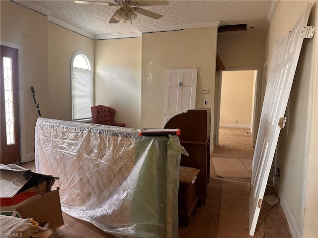 bedroom featuring ceiling fan, a textured ceiling, crown molding, and baseboards