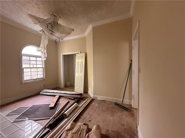 unfurnished room with a textured ceiling, crown molding, baseboards, and wood finished floors