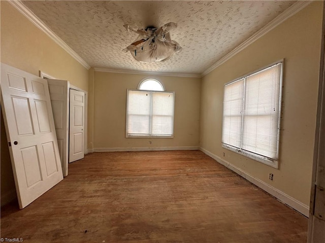 unfurnished bedroom with a textured ceiling, multiple windows, wood finished floors, and ornamental molding