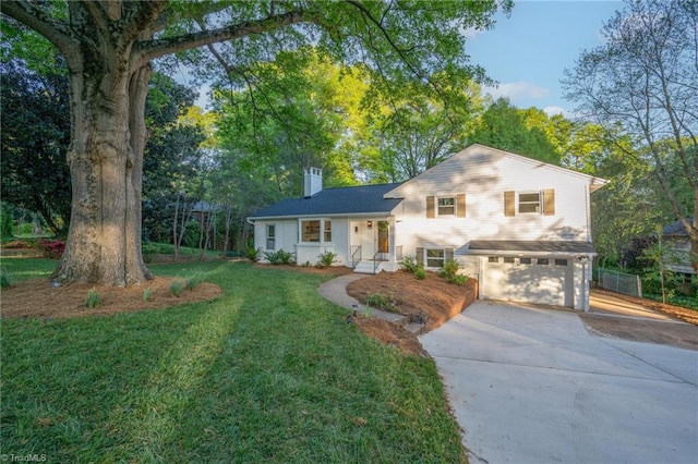 tri-level home featuring concrete driveway, a garage, a front yard, and a chimney
