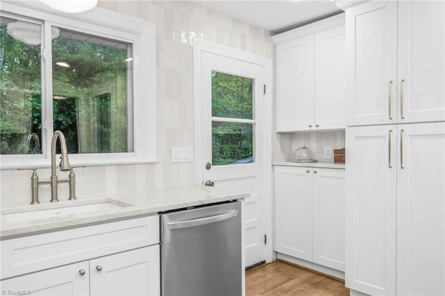 kitchen featuring dishwasher, a sink, light stone countertops, white cabinets, and light wood-type flooring