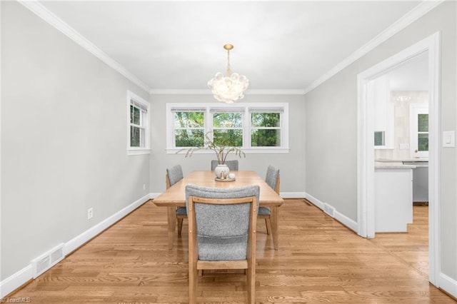 dining room with a chandelier, ornamental molding, baseboards, and light wood-type flooring