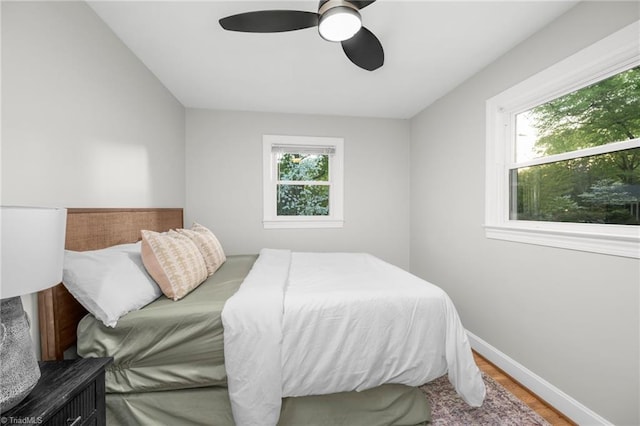 bedroom with multiple windows, wood finished floors, baseboards, and a ceiling fan