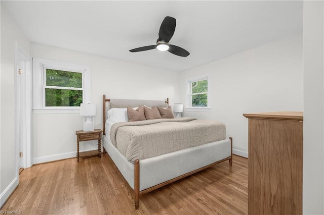 bedroom with light wood-style floors, baseboards, and a ceiling fan