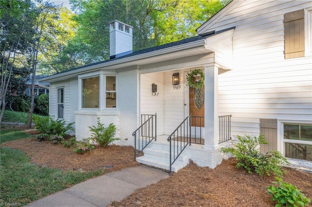 property entrance featuring a chimney and brick siding