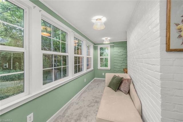 sunroom / solarium featuring brick wall, carpet floors, baseboards, and ornamental molding