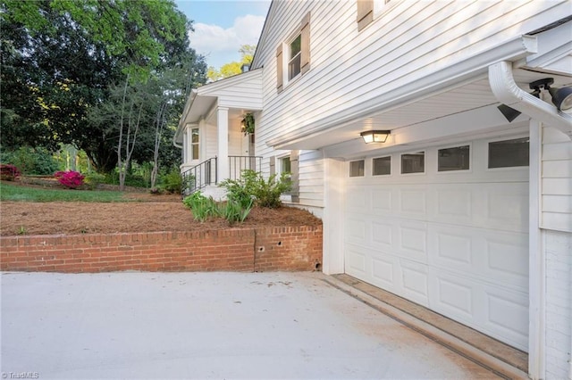 view of side of home featuring an attached garage and concrete driveway