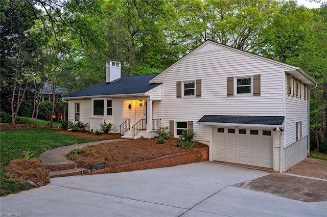 tri-level home featuring concrete driveway, a chimney, a garage, roof with shingles, and view of scattered trees