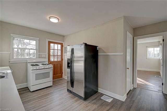 kitchen with stainless steel fridge, white gas range oven, and light wood-type flooring