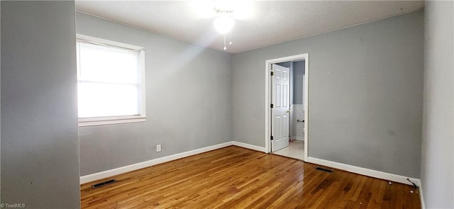 unfurnished bedroom featuring ensuite bathroom and wood-type flooring