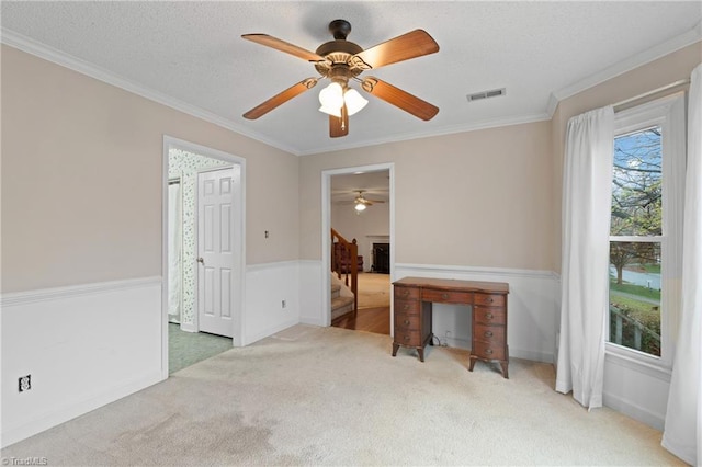 empty room with carpet, ceiling fan, crown molding, and a textured ceiling