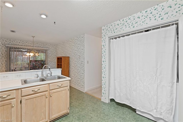 kitchen featuring light brown cabinets, sink, decorative light fixtures, a textured ceiling, and a notable chandelier