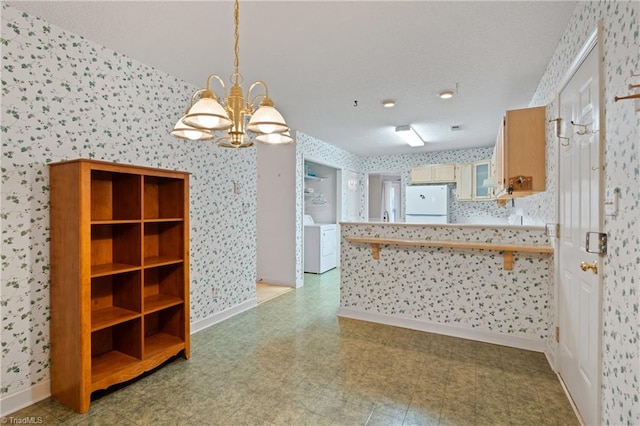 kitchen with kitchen peninsula, pendant lighting, white fridge, and an inviting chandelier