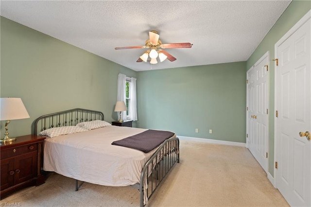 bedroom with two closets, a textured ceiling, light colored carpet, and ceiling fan