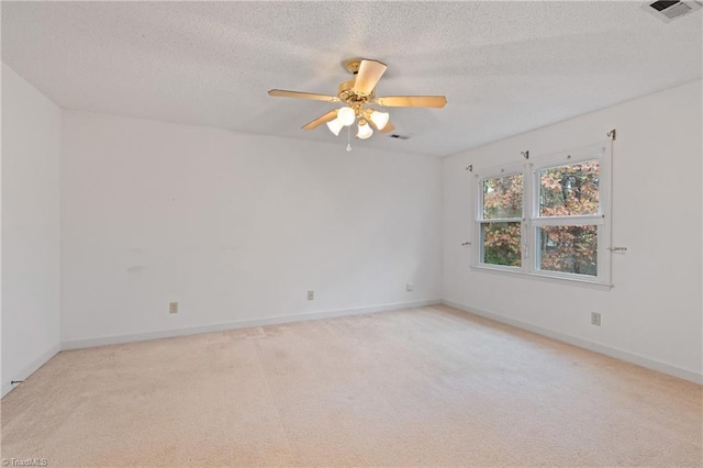 empty room featuring ceiling fan, light colored carpet, and a textured ceiling