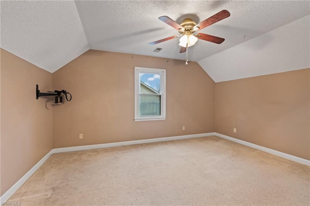 additional living space featuring a textured ceiling, light colored carpet, vaulted ceiling, and ceiling fan