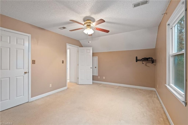 unfurnished bedroom featuring a textured ceiling, light colored carpet, ceiling fan, and lofted ceiling