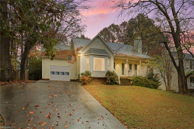 view of front of house with a porch, a yard, and a garage