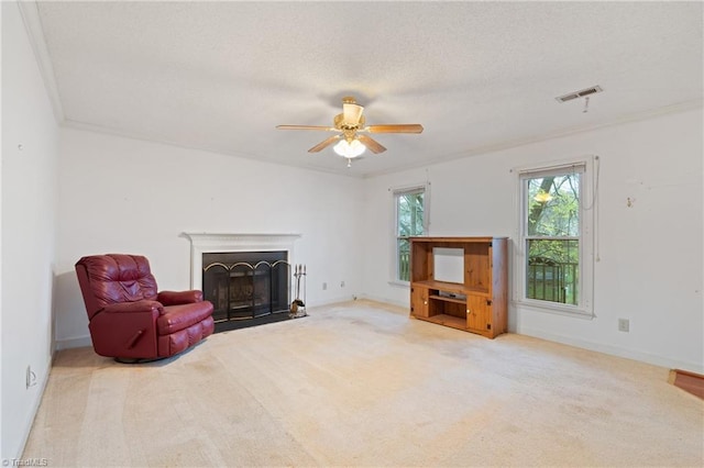 living area featuring carpet, ceiling fan, crown molding, and a textured ceiling