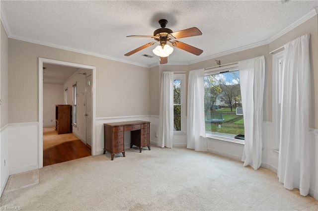 carpeted spare room with ceiling fan, a textured ceiling, and ornamental molding