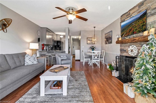 living room featuring dark hardwood / wood-style floors, ceiling fan, and a fireplace