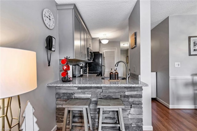 kitchen with gray cabinetry, light stone countertops, and a textured ceiling