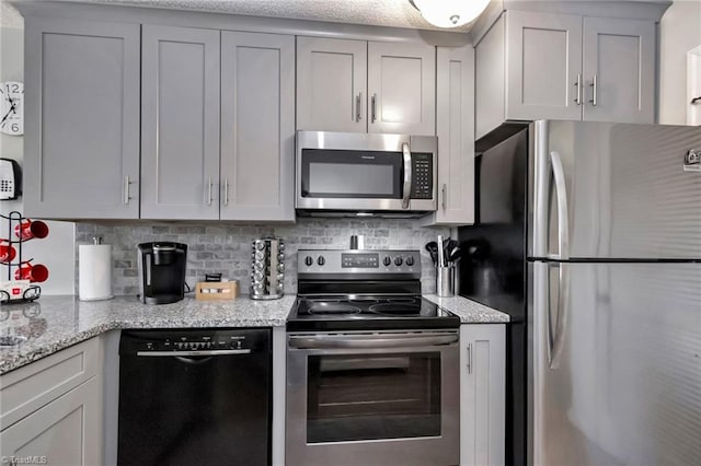 kitchen with decorative backsplash, light stone countertops, and appliances with stainless steel finishes