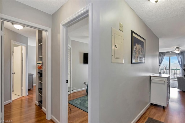 corridor featuring hardwood / wood-style flooring, a textured ceiling, and electric panel