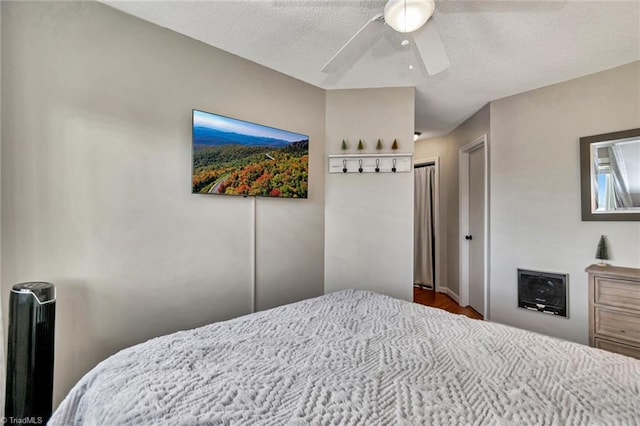 bedroom with ceiling fan, hardwood / wood-style floors, and a textured ceiling