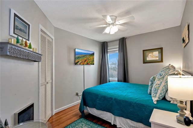 bedroom featuring ceiling fan, a closet, hardwood / wood-style floors, and a textured ceiling