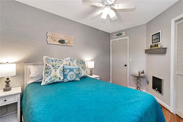 bedroom featuring a textured ceiling, heating unit, ceiling fan, hardwood / wood-style flooring, and a closet