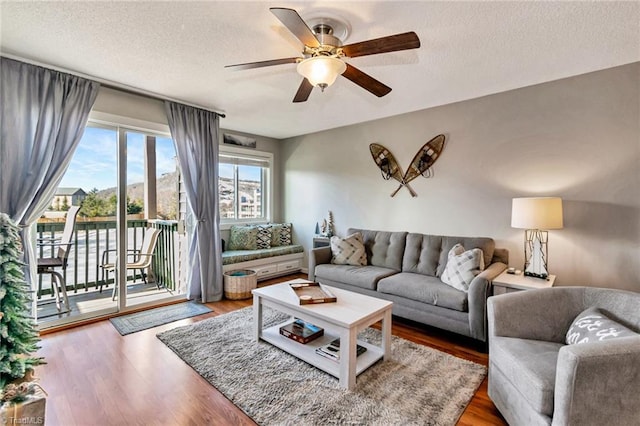 living room with ceiling fan, wood-type flooring, and a textured ceiling