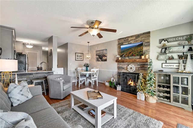 living room with ceiling fan, wood-type flooring, and a textured ceiling