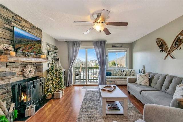 living room with a textured ceiling, ceiling fan, wood-type flooring, and a fireplace