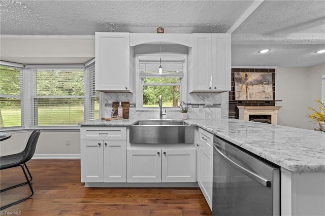 kitchen featuring decorative backsplash, white cabinetry, stainless steel dishwasher, and sink