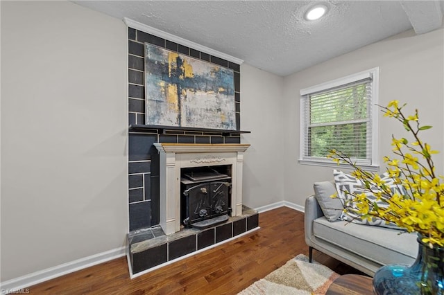 living room featuring a wood stove, hardwood / wood-style floors, and a textured ceiling