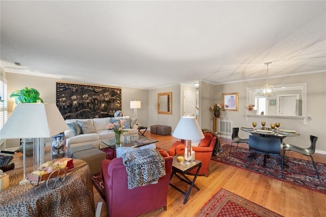 living room with crown molding, an inviting chandelier, and light hardwood / wood-style flooring