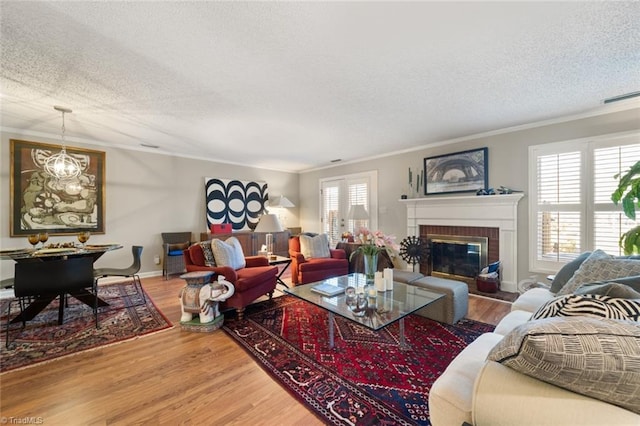 living room with wood-type flooring, ornamental molding, a fireplace, and a textured ceiling