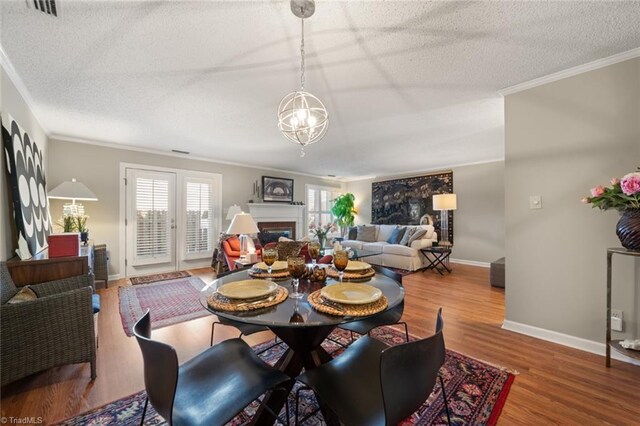 dining area featuring hardwood / wood-style flooring, crown molding, and a textured ceiling