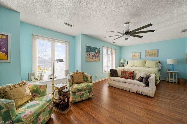 bedroom with ceiling fan, hardwood / wood-style floors, multiple windows, and a textured ceiling