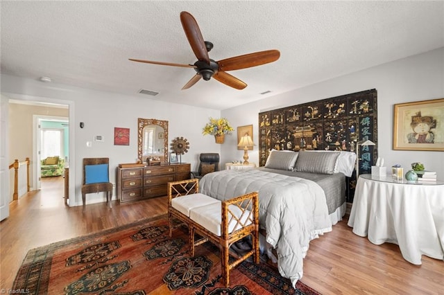 bedroom featuring ceiling fan, a textured ceiling, and light wood-type flooring