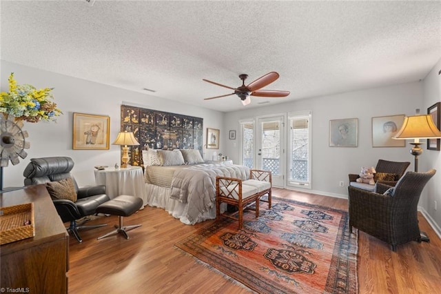 bedroom with access to exterior, hardwood / wood-style flooring, a textured ceiling, and ceiling fan