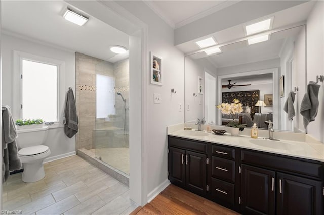 bathroom with hardwood / wood-style floors, a tile shower, vanity, toilet, and crown molding