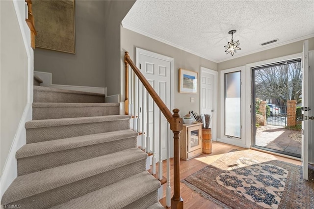 foyer entrance featuring ornamental molding, light hardwood / wood-style floors, and a textured ceiling