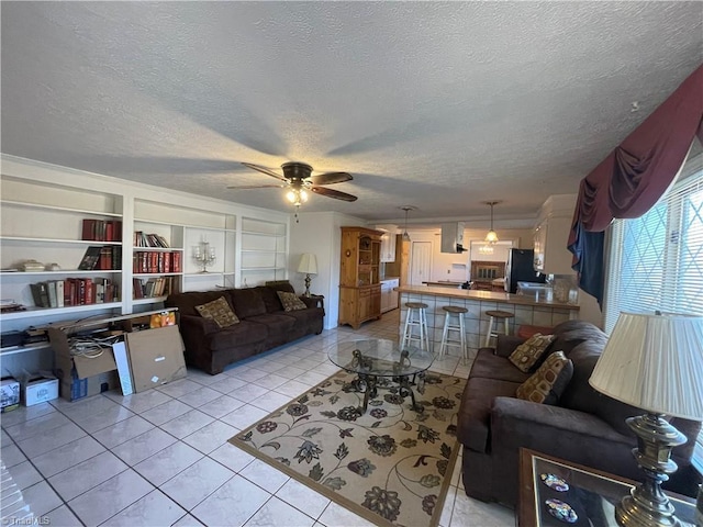 living room with a textured ceiling, built in shelves, light tile patterned flooring, and a ceiling fan