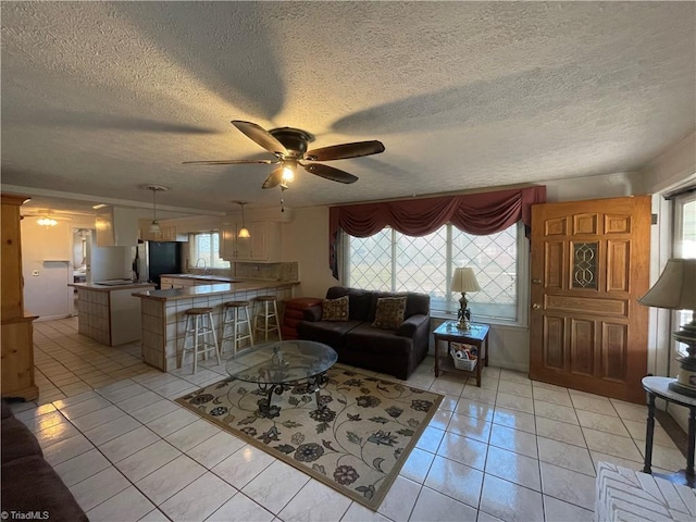 living room with light tile patterned floors, a textured ceiling, and a ceiling fan